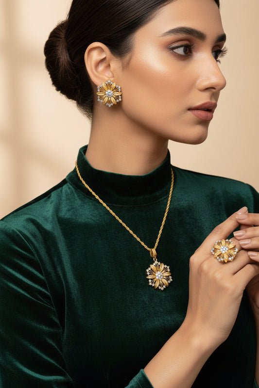 Woman wearing gold jewelry including a necklace, ring, and earrings against a beige background