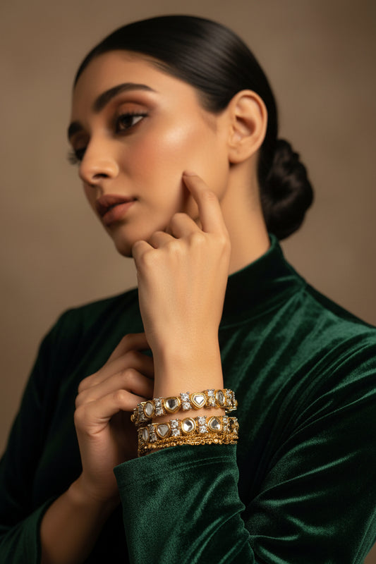 Pair of 24K gold plated kundani bangles set with flat kundan-style stones in a beaded gold frame, worn on the wrist