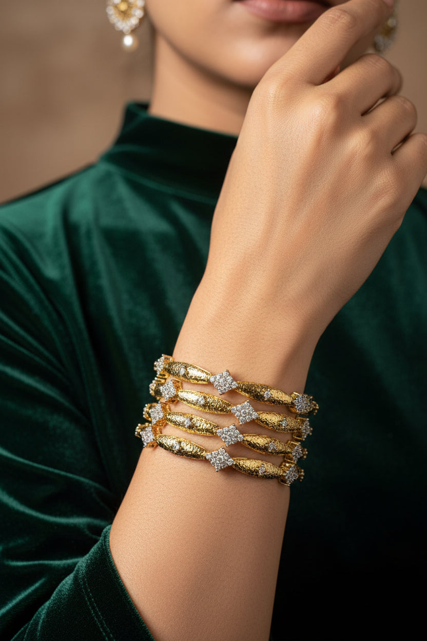 Set of four slim 24K gold plated bangles with diamond-cut gold bars and American zircon flower clusters, stacked on one wrist